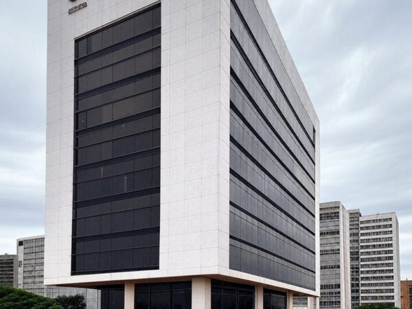 Edifício da Caesb em Brasília com documentos de concurso sob céu nublado, representando frustração de candidatos no DF.
