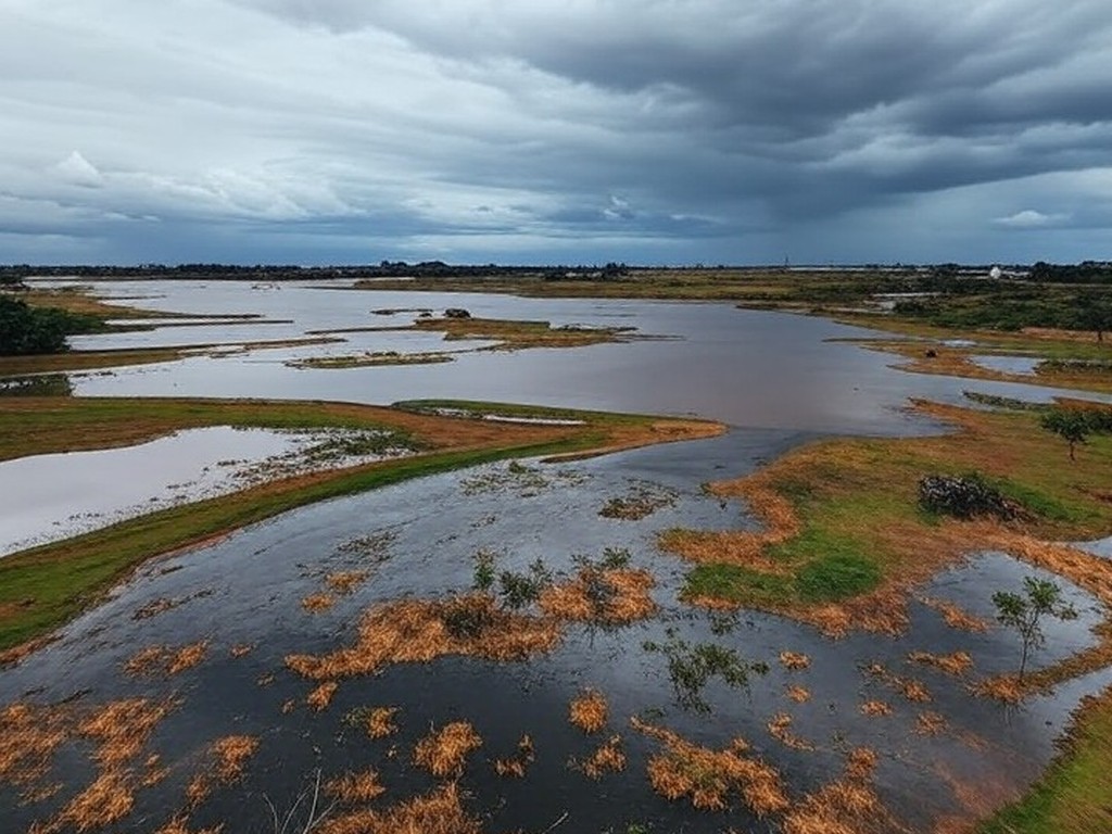 Transbordamento do Reservatório do Descoberto expondo riscos de inundações no Distrito Federal, com água invadindo margens e paisagem do planalto central.