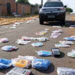 Rua em Ceilândia com viatura policial, pacotes suspeitos e máquinas de cartão, ilustrando falhas no combate ao tráfico de drogas.