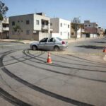 Cena de acidente de atropelamento em rua residencial do Paranoá Parque, com carro parado e fita de isolamento, sem pessoas.