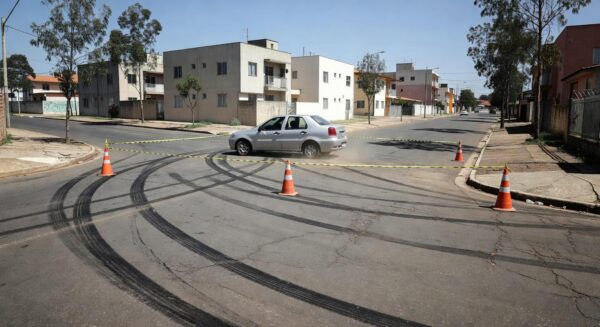 Cena de acidente de atropelamento em rua residencial do Paranoá Parque, com carro parado e fita de isolamento, sem pessoas.