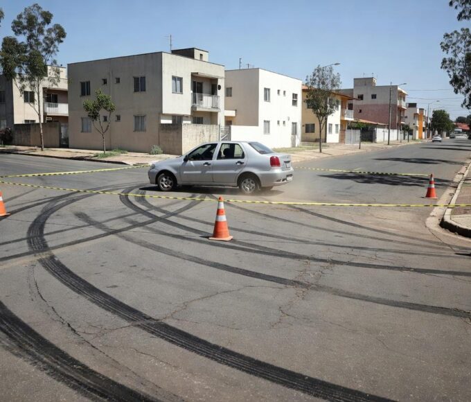 Cena de acidente de atropelamento em rua residencial do Paranoá Parque, com carro parado e fita de isolamento, sem pessoas.