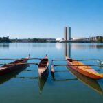 Canoas Va'a no Lago Paranoá durante Campeonato Brasileiro em Brasília, com skyline da cidade ao fundo.