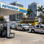 Posto de gasolina com viaturas da Polícia Federal investigando preços abusivos de combustíveis no Brasil.