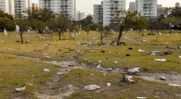 Área verde abandonada em Águas Claras, com grama seca, árvores murchas e lixo, expondo descaso com meio ambiente.